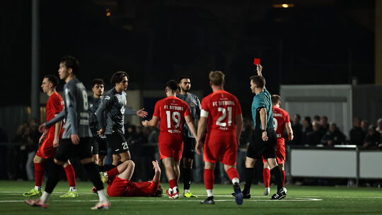 Schiedsrichter Jan-Hagen Engel zeigt hier Rot-Weiss-Akteur Giulio Multari (in Grau-Schwarz, Erster von rechts) in Bitburg die Ro Schiedsrichter Jan-Hagen Engel zeigt hier Rot-Weiss-Akteur Giulio Multari (in Grau-Schwarz, Erster von rechts) in Bitburg die Ro