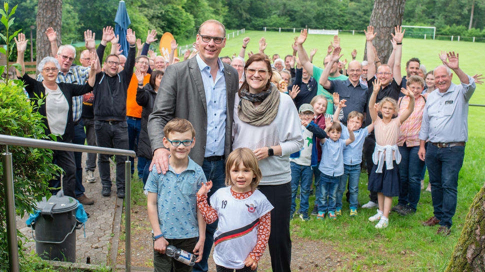 Matthias König und seine Familie freuen sich über den Wahlsieg. Im Hintergrund sind Freunde und Unterstützer, die gemeinsam am Sportplatz in Oberbrombach den Sieg feiern.