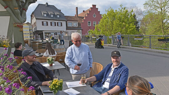 Gastgeber Werner Klopfer (stehend) freut sich, wenn Weinfreunde seine Tische und Stühle vor dem Brückenhaus nutzen, um regionale Gastgeber Werner Klopfer (stehend) freut sich, wenn Weinfreunde seine Tische und Stühle vor dem Brückenhaus nutzen, um regionale