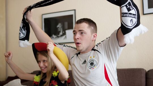 Ein Mann und seine Tochter jubeln zur Fußball-WM vor dem TV Ein Mann und seine Tochter jubeln zur Fußball-WM vor dem TV