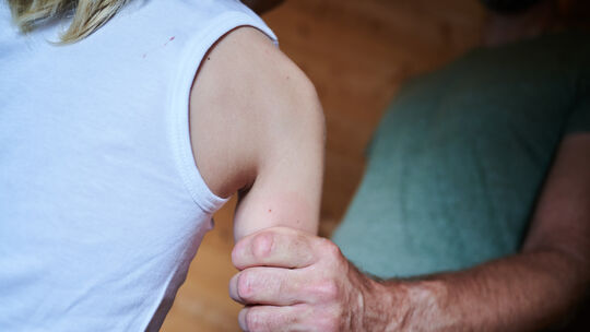 Ein Mann hält ein Kind fest am Arm (Symbolbild). Ein Mann hält ein Kind fest am Arm (Symbolbild).