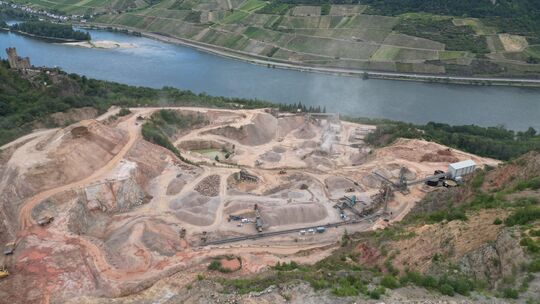 Der Steinbruch in Trechtingshausen gleich neben der Burg Sooneck (ganz links im Bild) ist die zentrale Produktionstätte der de B Der Steinbruch in Trechtingshausen gleich neben der Burg Sooneck (ganz links im Bild) ist die zentrale Produktionstätte der de B