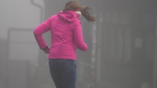 Frau kämpft auf dem Großen Feldberg im Taunus gegen Wind an Frau kämpft auf dem Großen Feldberg im Taunus gegen Wind an