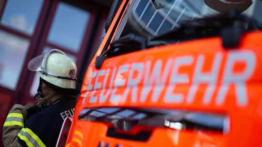 Feuerwehrmann steht neben einem Feuerwehrauto (Symbolbild) Feuerwehrmann steht neben einem Feuerwehrauto (Symbolbild)